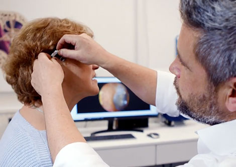 [Matt Cannon is fitting a hearing aid onto a patient]